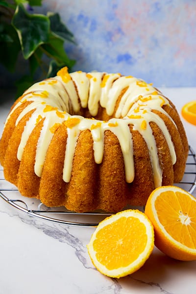 orange bundt cake topped with cream cheese frosting and orange zest