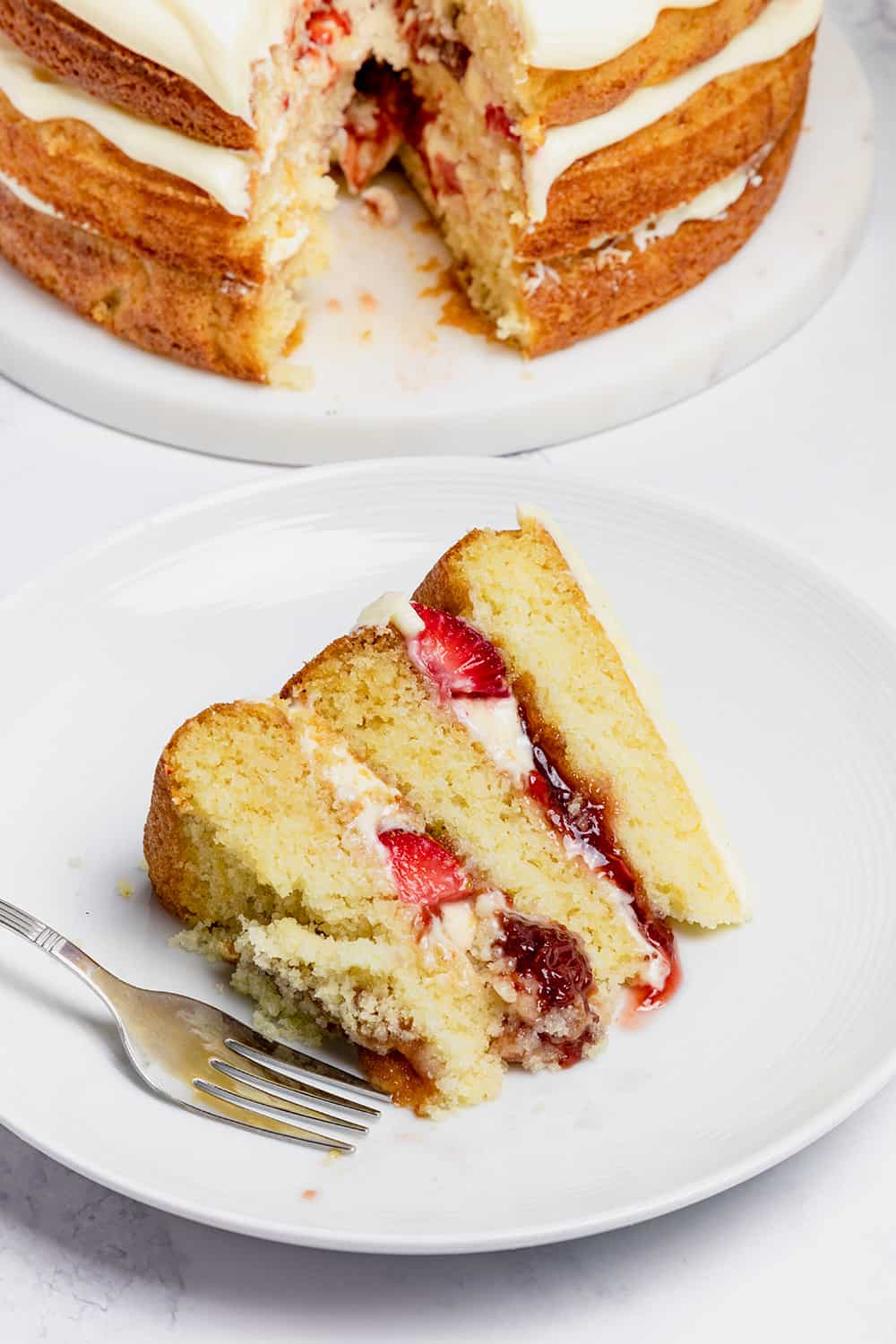 a slice of strawberry jam cake on a plate with a fork