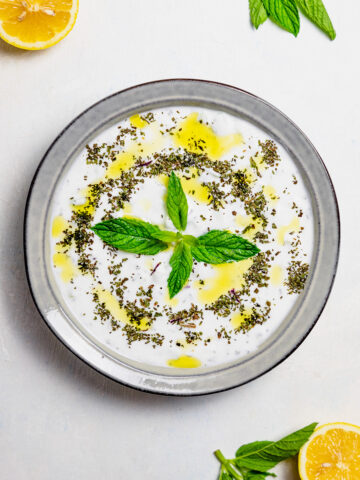 cucumber, mint, yogurt salad in a plate. Drizzled with olive oil and fresh mint.