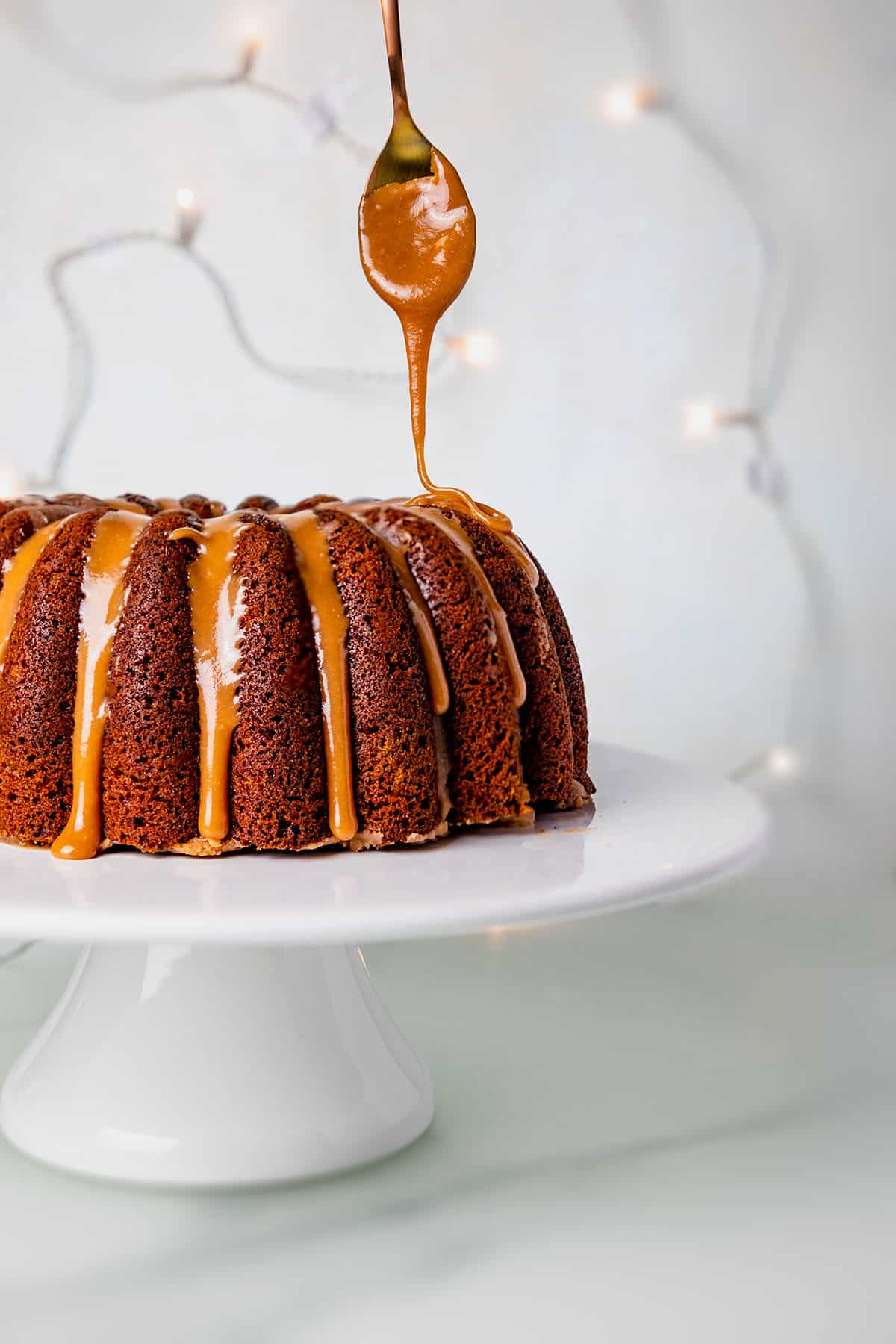 gingerbread bundt cake being decorated with caramel sauce